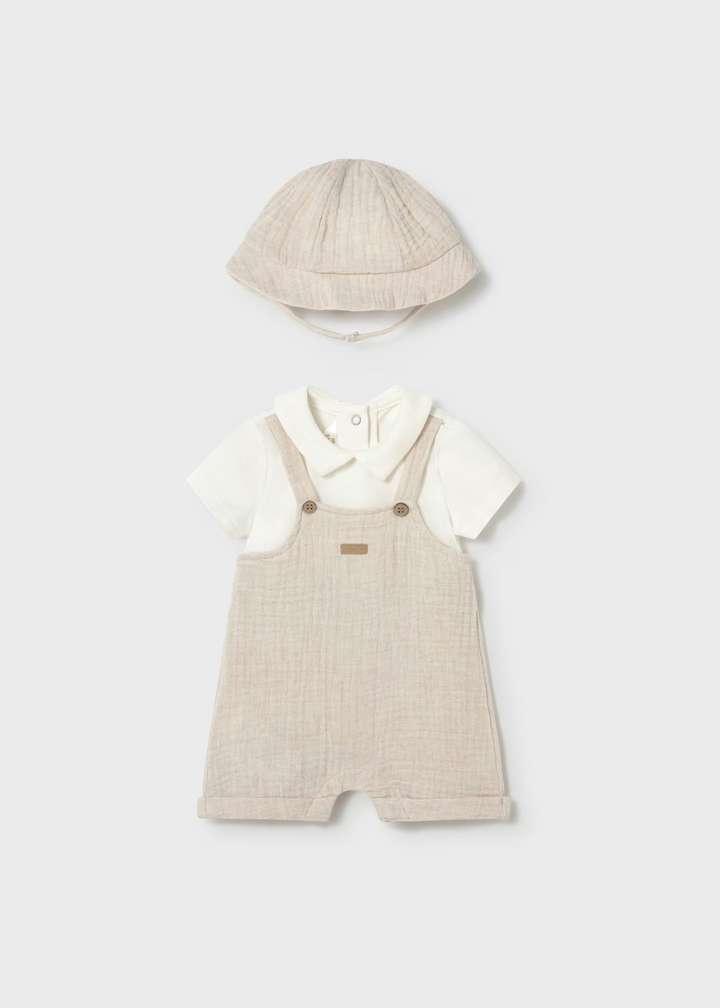 Baby outfit with beige overalls, white shirt, and hat on a light gray background