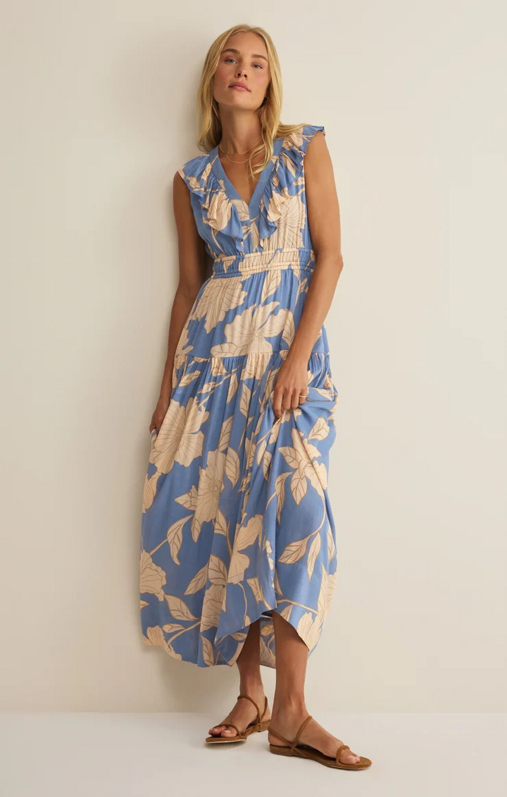 Woman wearing a blue and beige floral dress against a plain z supply background