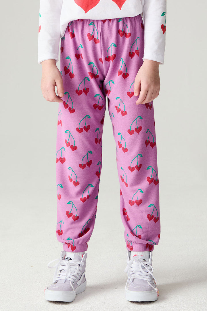 Front view of a girl wearing the Chaser Allover Sweethearts Girls Jogger on a neutral background with sneakers and shirt; pants only, coordinating tops sold separately