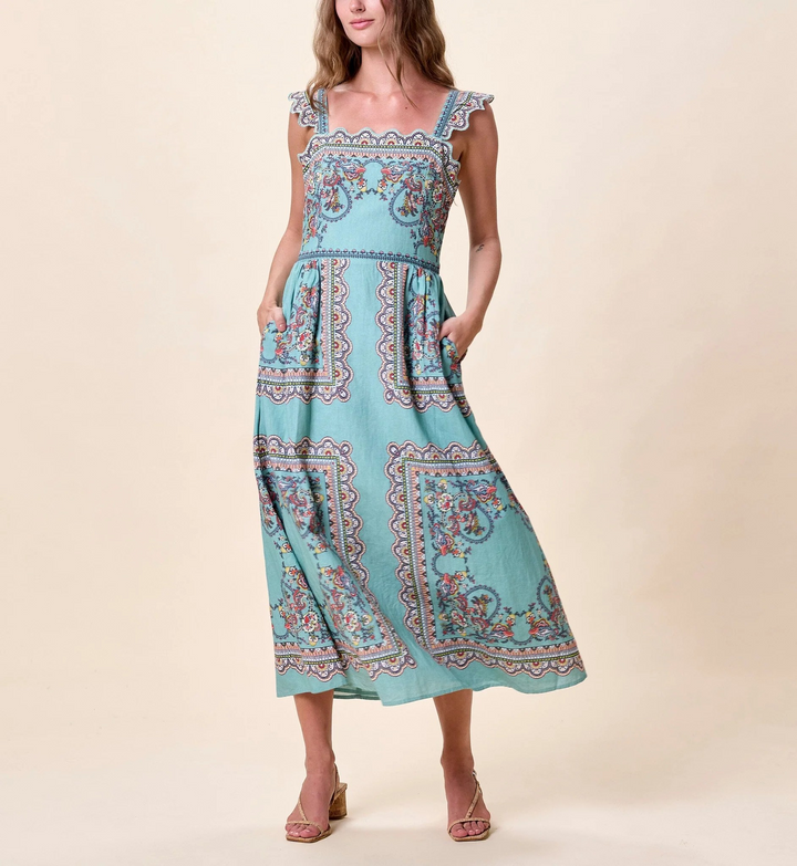 Woman wearing a turquoise dress with a pattern on a beige background