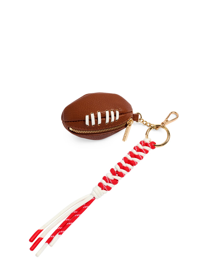 A football-shaped zippered coin purse in brown faux leather with white laces, attached to a gold-tone key ring and a red-and-white braided cord tassel, shown on a plain white background.