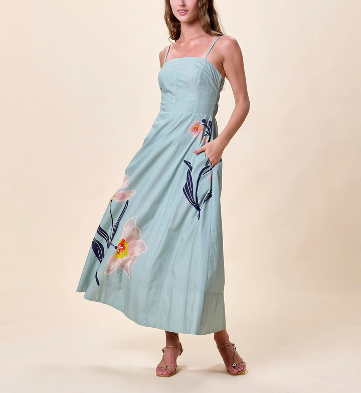 Woman wearing a light blue dress with floral patterns on a beige background