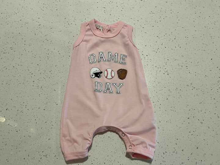 Pink baby romper with 'Game Day' text and sports-themed graphics on a speckled surface.