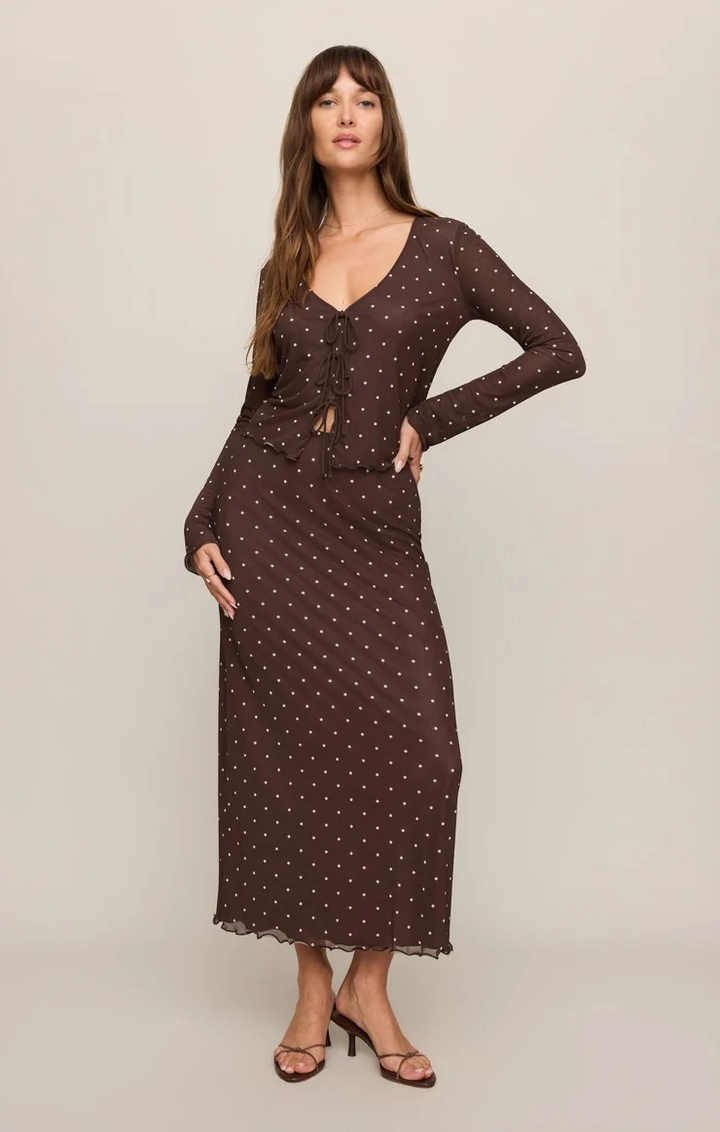 Woman wearing a brown polka dot dress against a beige background