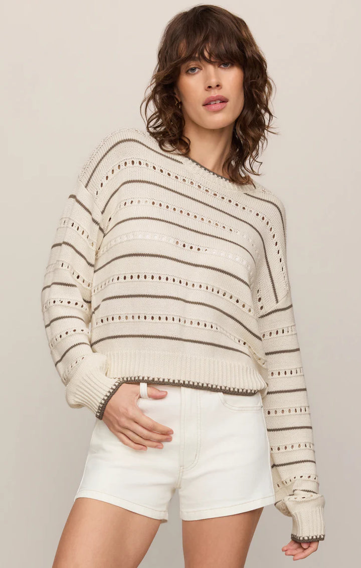 Woman wearing a striped sweater and white shorts against a plain z supply background